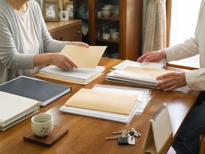 実家のテーブルで家族が書類を分類する様子