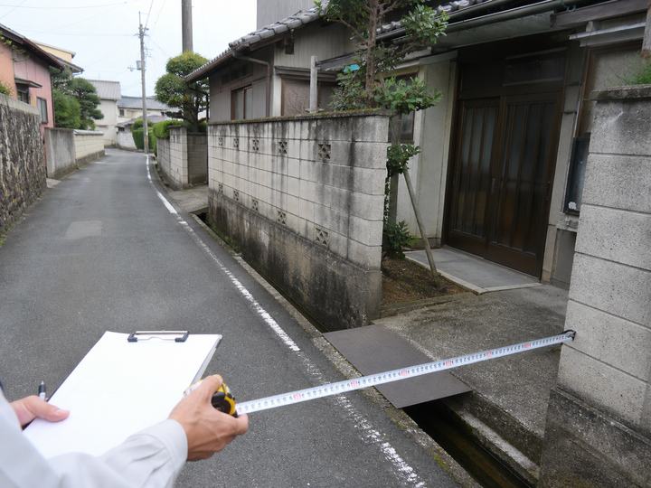 古家の前面道路と側溝、敷地入口を確認する様子
