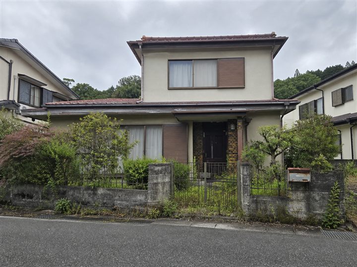 庭の草が少し伸び、雨戸が閉まった空き家の外観イメージ