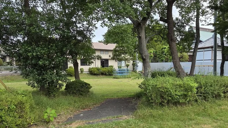 磐田市内の住宅地。公園の木立の向こうに平屋と瓦屋根の家が見える